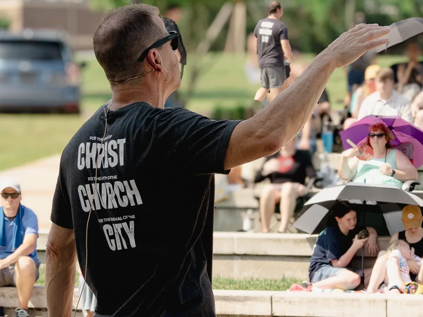 Rob preaching outdoors, shirt reading for Christ, for the Church, for the City